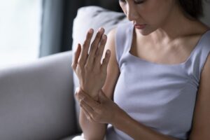 rheumatoid-arthritis-2 | Aaria Rheumatology Woman examining her painful hand and wrist, showing possible symptoms of arthritis, joint inflammation, or autoimmune disease.
